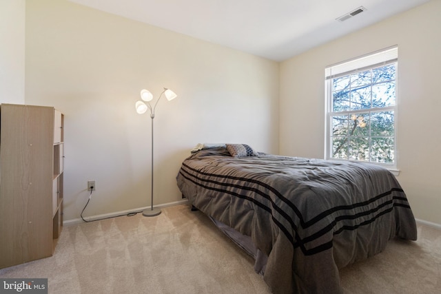 bedroom with baseboards, visible vents, and light carpet