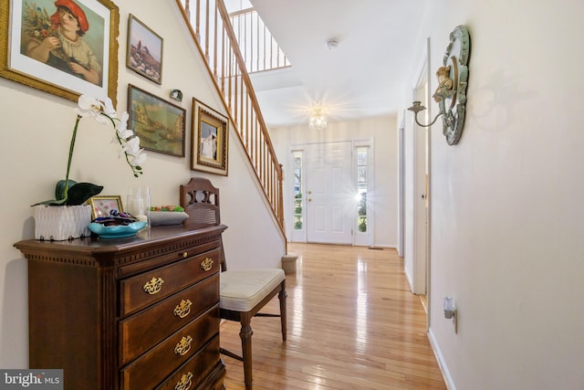 foyer entrance featuring stairway, baseboards, and light wood-style flooring