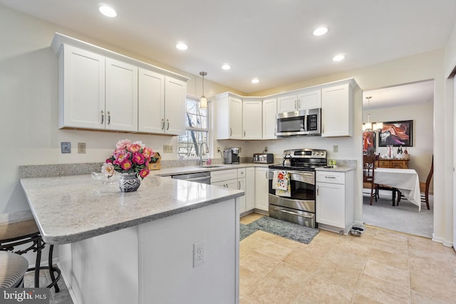 kitchen with a sink, recessed lighting, appliances with stainless steel finishes, a peninsula, and white cabinets