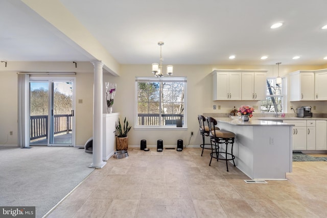 kitchen featuring visible vents, decorative columns, plenty of natural light, light countertops, and white cabinets