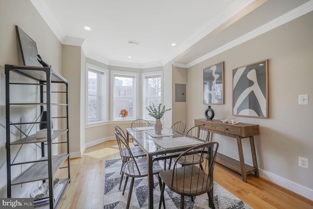 dining room featuring ornamental molding, baseboards, visible vents, and light wood finished floors