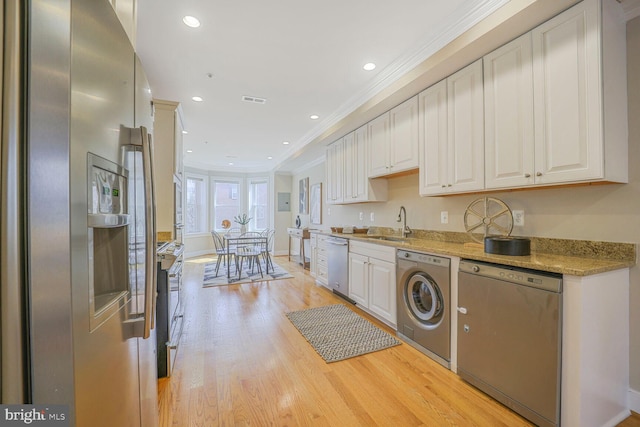 kitchen with stainless steel appliances, washer / clothes dryer, a sink, and white cabinets