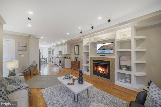 living room with light wood-style floors, ornamental molding, and built in features