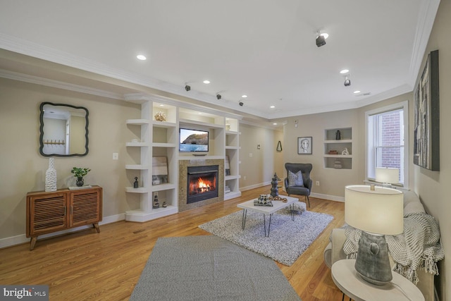 living room featuring built in features, a tile fireplace, baseboards, and light wood finished floors