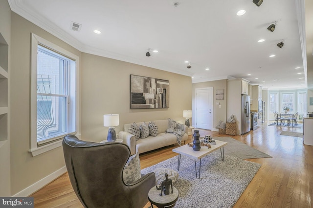 living area with ornamental molding, light wood-style flooring, and baseboards