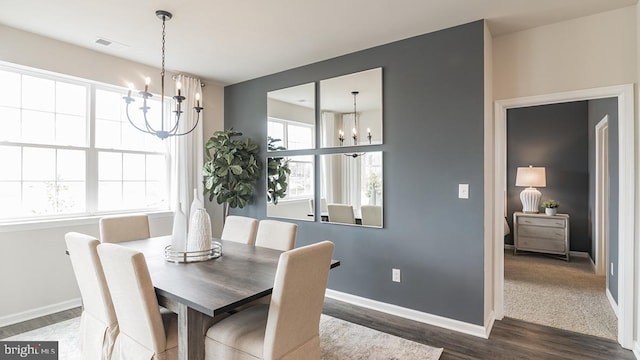 dining area featuring dark wood-type flooring, visible vents, a notable chandelier, and baseboards