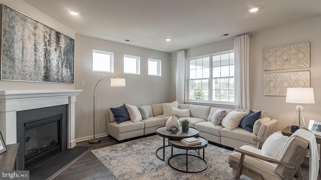 living room with recessed lighting, visible vents, dark wood-style flooring, and a glass covered fireplace