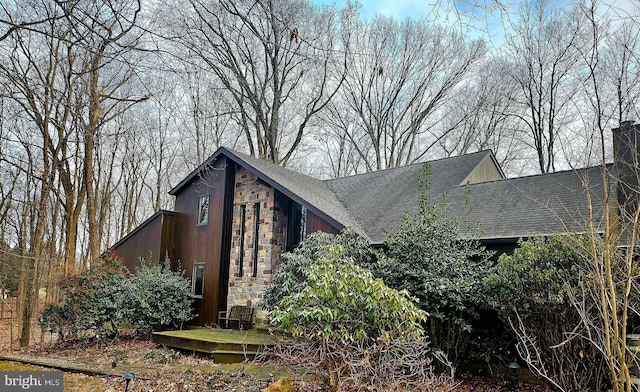 view of side of home with roof with shingles