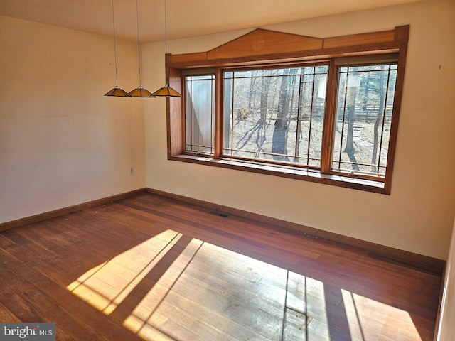 unfurnished room with visible vents, baseboards, and dark wood-type flooring