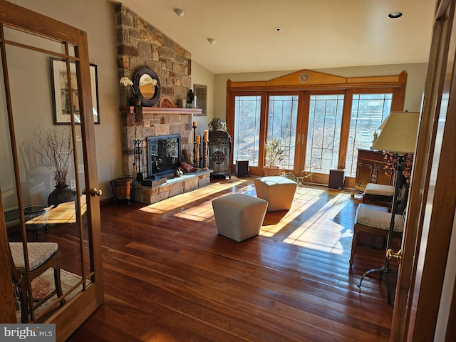 living area with a stone fireplace, vaulted ceiling, wood finished floors, and french doors