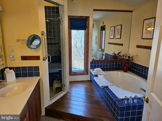 full bathroom featuring vanity, a stall shower, wood-type flooring, a garden tub, and toilet