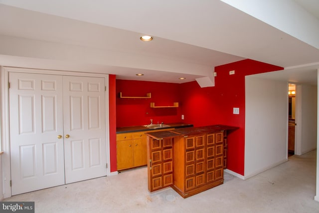 kitchen featuring dark countertops, baseboards, recessed lighting, brown cabinets, and a sink