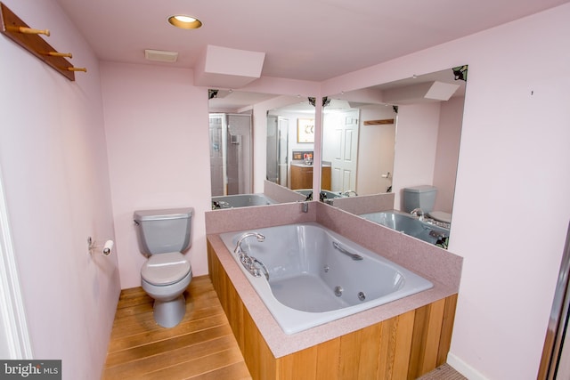 full bath featuring toilet, wood finished floors, recessed lighting, and a whirlpool tub