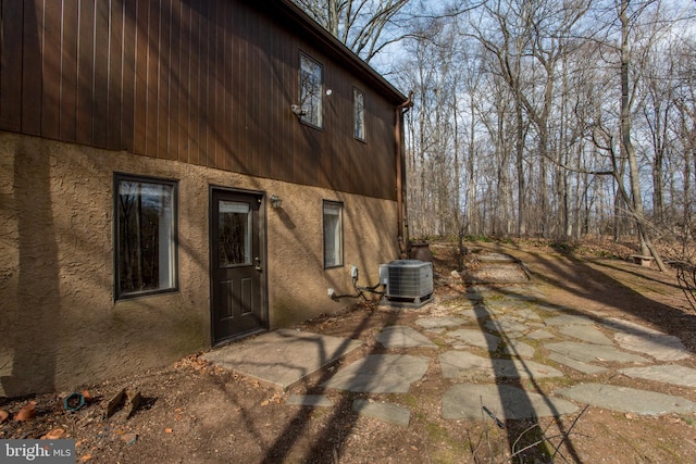 view of side of property with a patio, central air condition unit, and stucco siding