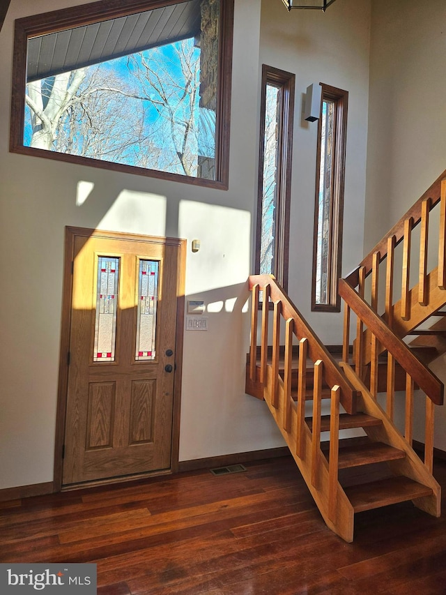 entrance foyer with stairway, wood finished floors, and baseboards