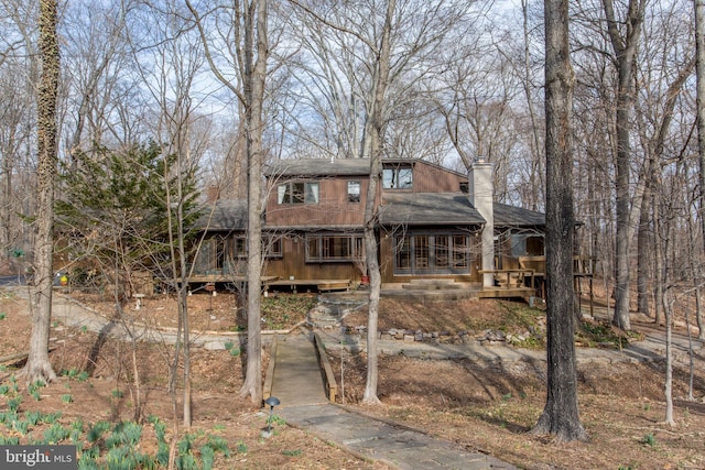 view of front of house featuring a chimney and a shingled roof