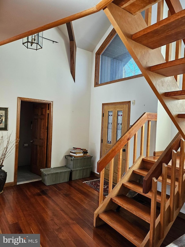 stairs with beamed ceiling, wood finished floors, baseboards, and high vaulted ceiling