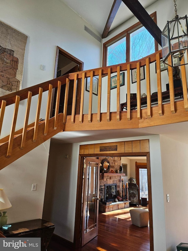 stairway featuring a wealth of natural light, visible vents, a high ceiling, and wood finished floors