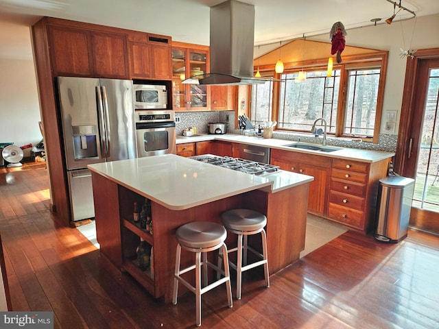 kitchen featuring island range hood, brown cabinets, appliances with stainless steel finishes, and a sink