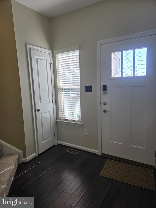 entrance foyer featuring stairs, dark wood-style flooring, visible vents, and baseboards