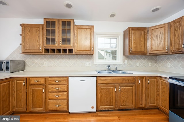 kitchen featuring range with electric cooktop, a sink, dishwasher, light wood finished floors, and stainless steel microwave