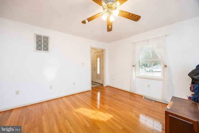 empty room with a ceiling fan, light wood-type flooring, visible vents, and baseboards