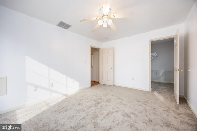 unfurnished bedroom featuring carpet floors, a ceiling fan, visible vents, baseboards, and a spacious closet