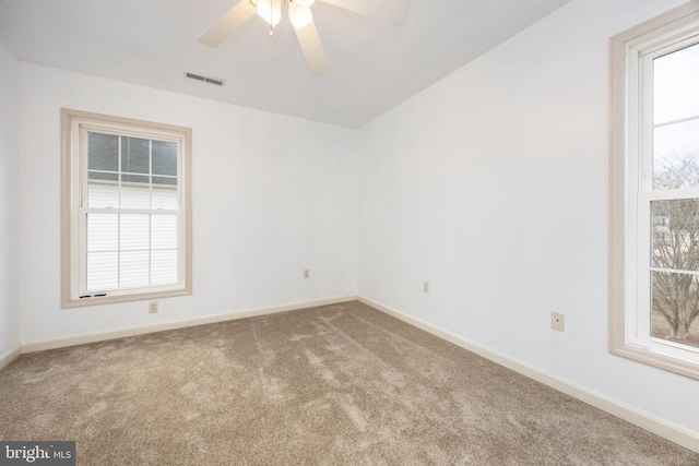 empty room featuring a healthy amount of sunlight, visible vents, baseboards, and carpet flooring