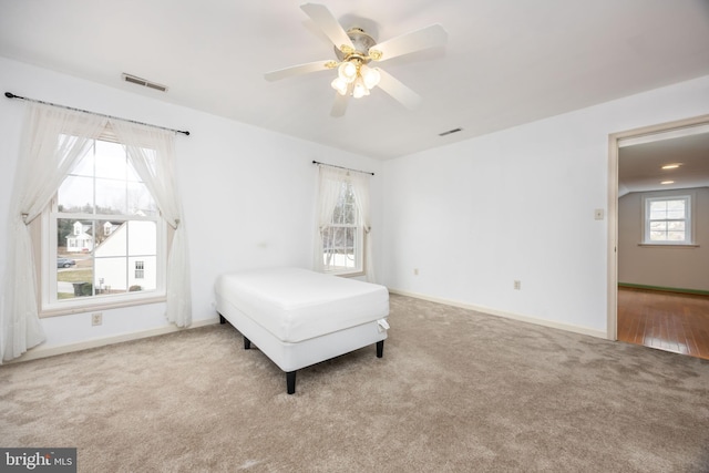 unfurnished bedroom with a ceiling fan, carpet, visible vents, and baseboards