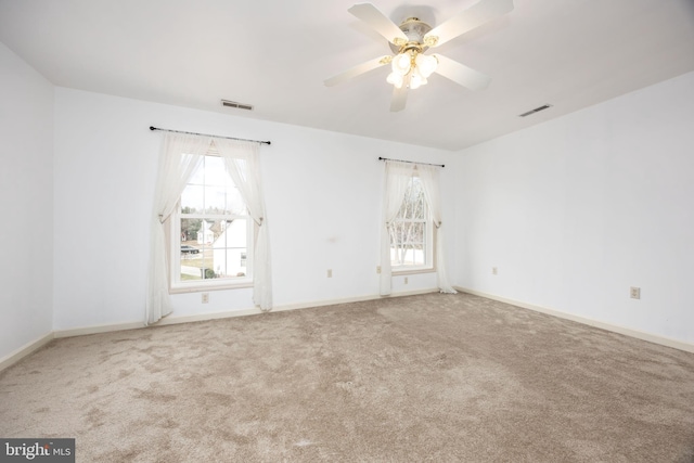 carpeted spare room with baseboards, visible vents, and a ceiling fan