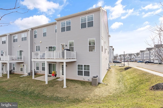 back of house featuring a residential view, central AC, and a yard