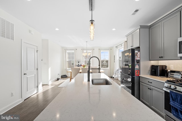 kitchen featuring gas range, freestanding refrigerator, a sink, and gray cabinetry