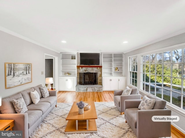 living room with crown molding, recessed lighting, a fireplace, and light wood-style floors