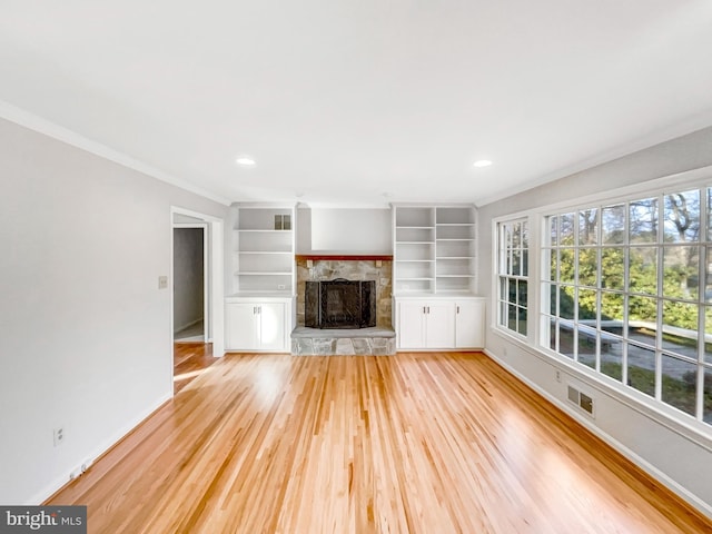 unfurnished living room with baseboards, visible vents, light wood-style flooring, crown molding, and a fireplace