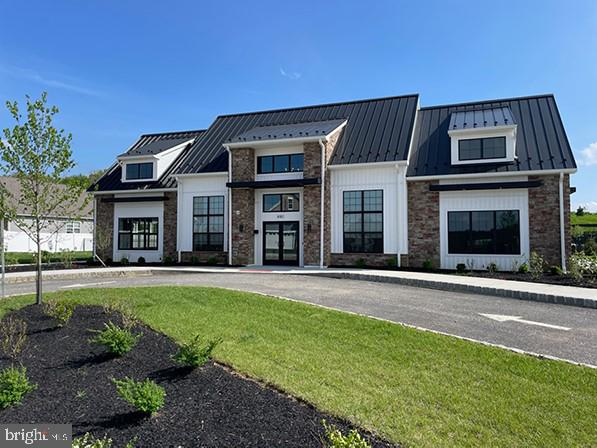 modern inspired farmhouse with stone siding, a front yard, a standing seam roof, and metal roof