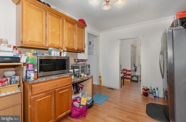 kitchen with stainless steel appliances, light wood-type flooring, visible vents, and brown cabinets