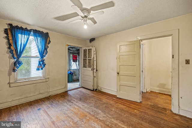 interior space with baseboards, a textured ceiling, a ceiling fan, and hardwood / wood-style floors