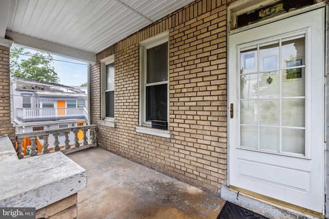 property entrance with covered porch and brick siding