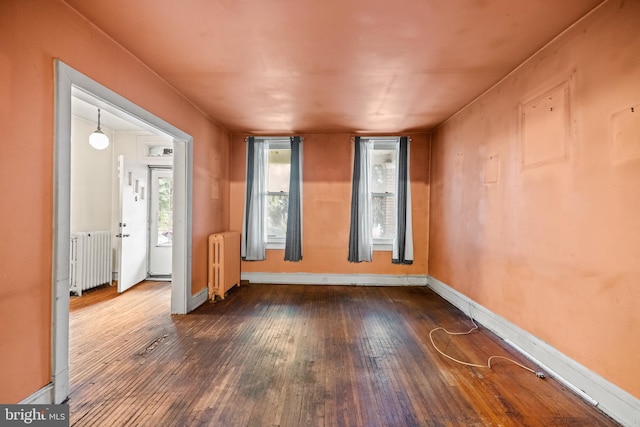 unfurnished room with radiator, baseboards, and hardwood / wood-style floors