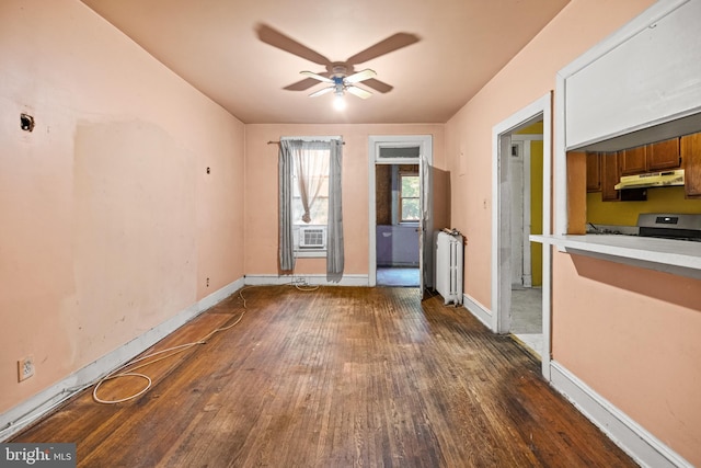 unfurnished living room with dark wood-style floors, baseboards, radiator heating unit, and a ceiling fan