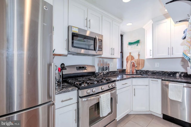 kitchen featuring stainless steel appliances, white cabinetry, a sink, and dark stone countertops