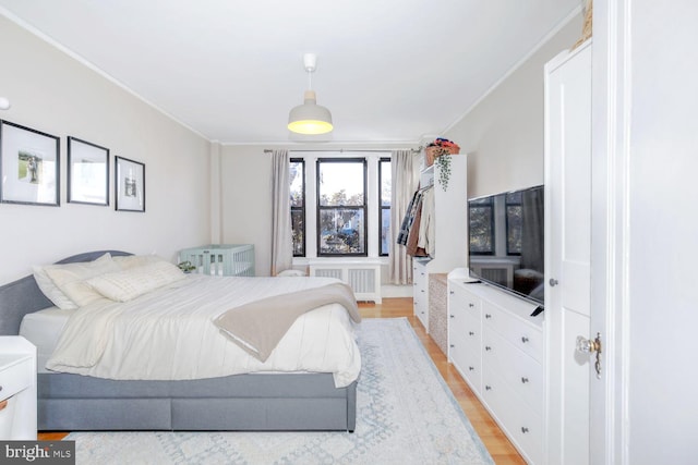 bedroom with light wood finished floors, radiator heating unit, and ornamental molding