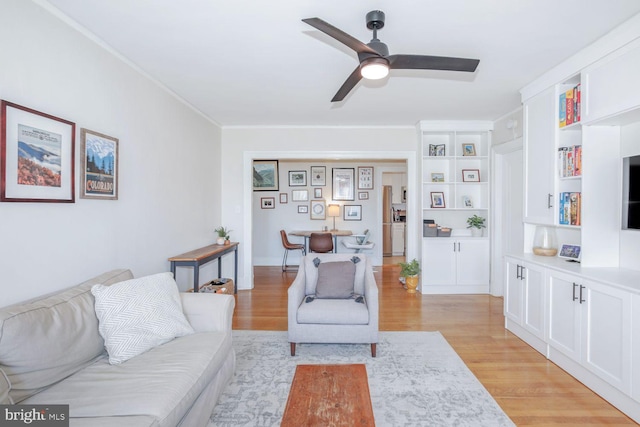 living room featuring ornamental molding, light wood-type flooring, and a ceiling fan