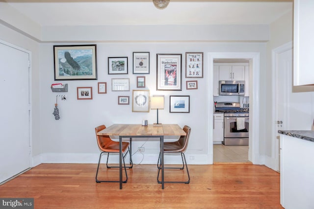 dining space with light wood-style flooring and baseboards