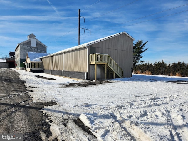 snow covered structure featuring an outbuilding