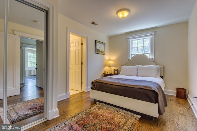 bedroom with visible vents, multiple windows, baseboards, and wood finished floors