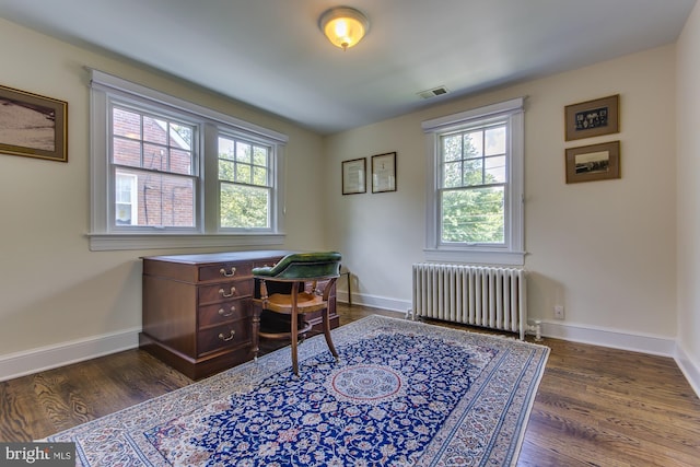 home office with dark wood-style floors, visible vents, radiator heating unit, and baseboards