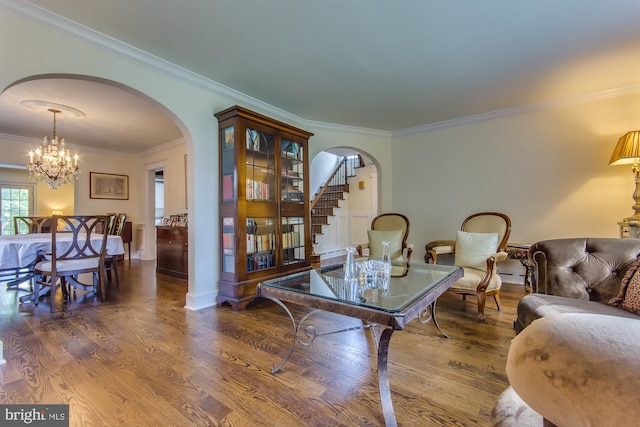 living area with stairs, wood finished floors, arched walkways, and ornamental molding