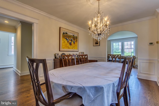 dining area with dark wood finished floors, plenty of natural light, a decorative wall, and crown molding