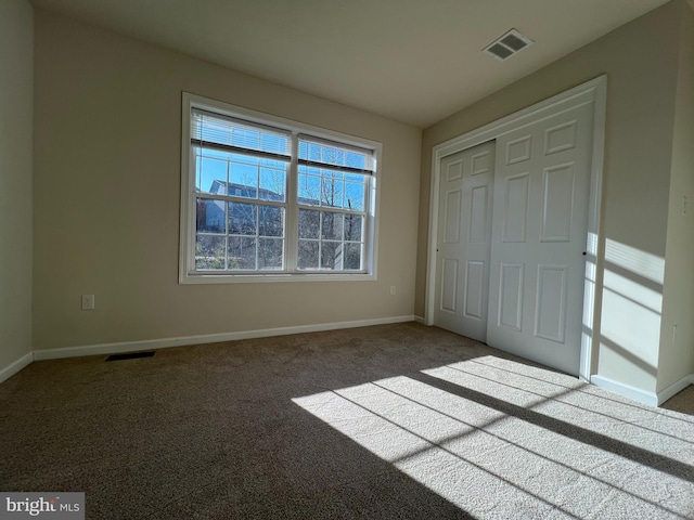 unfurnished bedroom with carpet floors, baseboards, visible vents, and a closet